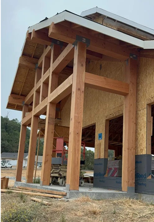 Post-and-beam covered entry under construction on a new home, with heavy timber posts and galvanized steel connectors.